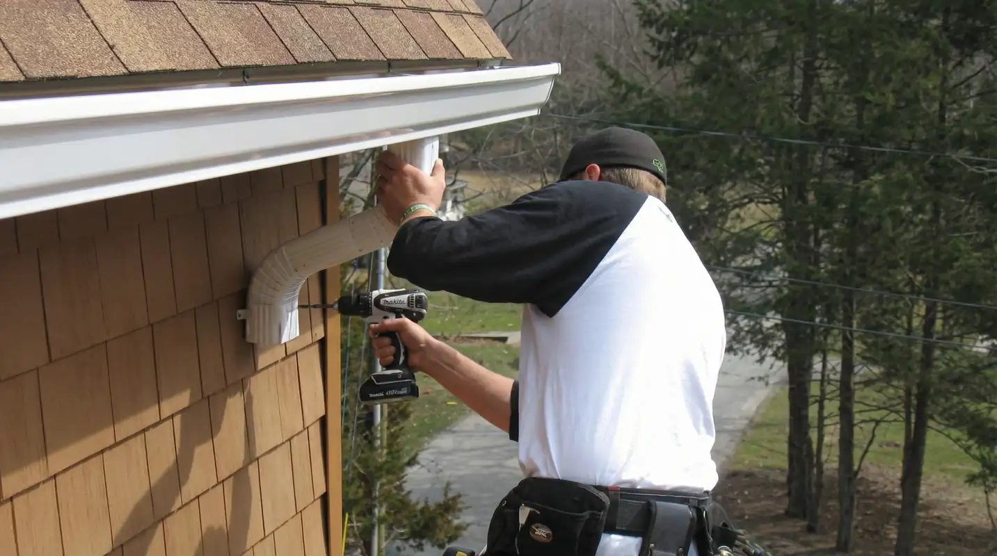Professional contractor installing tan vinyl siding panels on a residential home exterior in Fort Wayne, IN